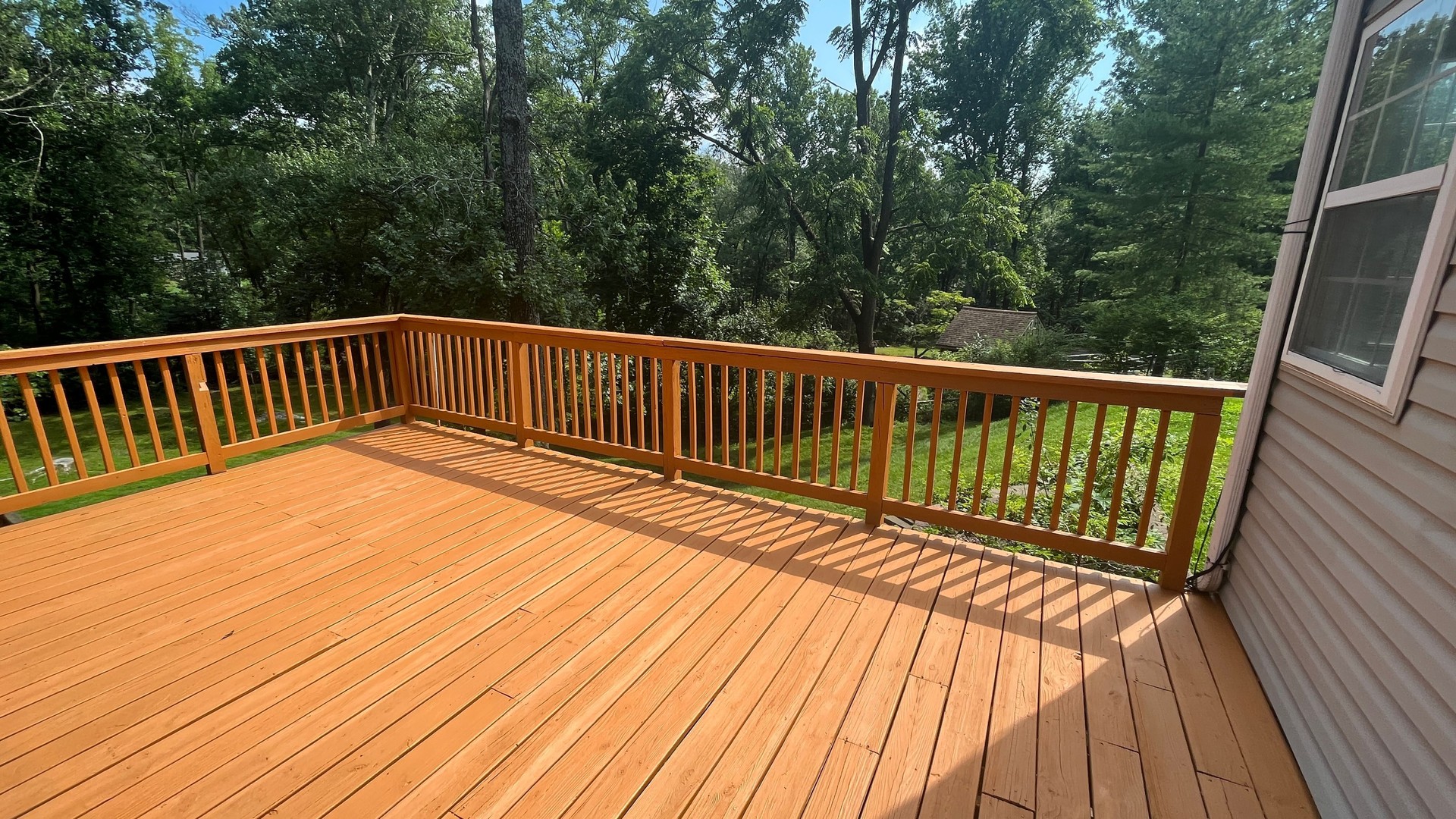 a wooden deck with sliding doors next to a green tree